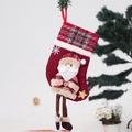 Detail van een rode kerstsok met ruitpatronen, pluche rand en kerstman-pop - Kerstman