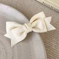 Dettaglio del fermaglio per capelli a fiocco in raso crema con doppia trama - Beige