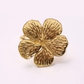Macro shot of golden flower napkin ring with detailed metal texture on five petals - Gold