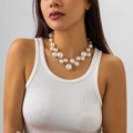 Detail of punk style layered necklace with oversized pearls and silver chain on model - White