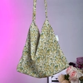 Close-up of floral canvas tote bag featuring green and yellow floral patterns and side label - Light Green Camellia