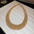 Detalle del collar gargantilla dorado de varias capas con resorte en base blanca - Gargantilla de Resorte Grande