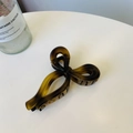 Detail view of a large translucent amber bow hair claw clip with smooth glossy finish - Matte Light Tortoise