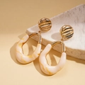Detail of geometric resin earrings with gold metallic texture on minimalist stone display - Silver Pin - Cream White