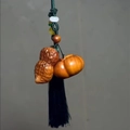 Detailed wood carving of a peanut and pumpkin pendant with long black silk tassel - Aged Cypress Peanut Charm
