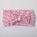 Detail of baby nylon headband featuring a large bow with red baseball heart patterns - White Red Heart Pattern