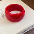 Modern thick red acrylic resin bangle with geometric faceted finish on a book - Rose Red