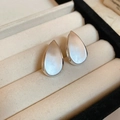 Detailed close-up of matte silver teardrop earrings on a beige velvet jewelry display case - Teardrop Matte Studs (30#)