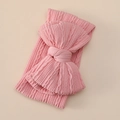 Détail d'un bandeau en tricot rose pour bébé avec texture douce et grand nœud décoratif - Rose