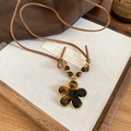 Detailed macro view of vintage leopard resin flower pendant on a brown cord necklace - Flower Shape (Tiger Eye) / Coffee