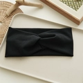 Close-up of a soft black twisted knot headband displayed on a minimal beige tray - Black