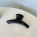 Vue détaillée d'une pince à cheveux noire à pois avec dents courbées sur fond blanc - Cintre Carré Noir / Noir