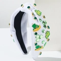 Detail of St. Patrick's Day headband with green rhinestones and Luck shamrock charms - White