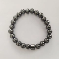 Polished black hematite stone bead bracelet with cylindrical accent on white background - Non-magnetic Hematite