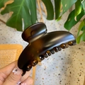 Close-up of a large glossy dark brown hair claw clip held by a hand in lifestyle setting - 10cm Yuanbao Claw / Matte Light Tortoise