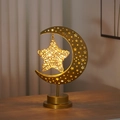 Détail d'une lampe lune dorée avec motifs d'étoiles et pendentif étoile lumineux - Lampe Étoile en Rotin Cadre Pentagramme / Blanc chaud