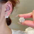 Eleganti orecchini a fiore in acrilico bianco con zirconi mostrati su modella e in mano - Stile 18 Orecchini a Bottone con Sfera Rotonda a Fiore di Zircone