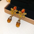 Primo piano di orecchini vintage a fiore in oro con zirconi ambra su scatola porta gioie - 34# Oro-Orecchini con Pendente a Sfera e Fiore Ambra