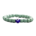 Dettaglio macro delle pietre laviche verdi porose e del ciondolo malocchio sul bracciale - Pietra Lavica Verde Occhio del Diavolo Blu