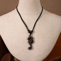 Detailed close-up of a Maori style resin seahorse pendant on a black woven cord necklace - Seahorse