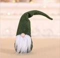 Green handmade Christmas gnome doll with tall hat and white beard in festive bokeh light - Green