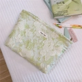 Dettaglio della pochette in tessuto verde menta con ricami floreali bianchi ed etichetta - verde chiaro