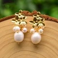 Elegant gold flower baroque pearl earrings displayed on a natural wood surface - Three-Flower Pearl Stud Earrings