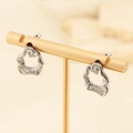 Minimalistische silberne unregelmäßige Creolen an einem goldenen Schmuckständer - Stahlfarbe