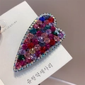 Macro shot of heart-shaped hair clip with colorful crystals on white packaging card - Red Green Multi-color