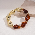 Dettaglio di bracciale con grosse perle in resina ambra e perle dorate lucide - Caffè Scuro