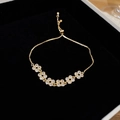 Macro detail of gold flower bracelet with zircon stones on premium black velvet - Gold