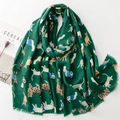 Detailed flat lay of dark green scarf with cartoon cat prints and frayed edge details - Green