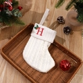 Knitted ivory Christmas stocking with red embroidered letter H and green holly leaf - Letter H