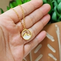 Golden stainless steel Faith mountain mustard seed necklace held against a green leaf - Gold Color Style 01