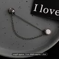 Detalle macro de la hebilla de cadena magnética para ajustar el largo de la camiseta - Negro