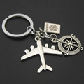 Detalle macro del llavero de viaje plateado con avión, pasaporte y brújula - Avión Pasaporte Brújula