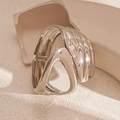 Macro-opname van zilveren golvende armband met een sculpturale gepolijste metaaltextuur - Asymmetrische Holle Open Armring / Zilver