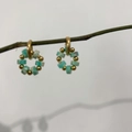 Detalle macro de pendientes de oro de 18K con piedras turquesas naturales en rama - Espaciador Verde Azulado