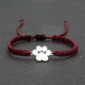 Close-up of handmade red woven lucky bracelet featuring a silver dog paw charm - Burgundy