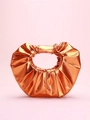 Detalle de bolso de mano plisado naranja metalizado con asa redonda en fondo rosa - Naranja