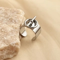 Detalle de anillo ancho plateado con diseño de hebilla en T sobre base de piedra - Color Acero