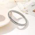 Minimalist silver flexible spring bracelet with metallic spiral design on white plate - Silver