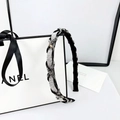 Detalle de una diadema trenzada de lujo con pedrería plateada sobre tela negra - Diamante Blanco y Gris Mineral