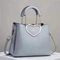 Close-up of light blue heart-shaped metal buckle on litchi texture leather handbag - Gray