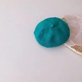 Teal knit beret hat for infants with spiral texture placed in a woven basket - Lake Blue