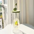Detail of avocado green glass cup with matching silicone lid and cute floral straw cap - Avocado + Lid + Straw + Dust Cap