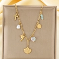 Dettaglio della collana con ciondoli dorati, conchiglia, perla, croce e delfino su catena - Stile Girasole Delfino Croce Conchiglia (KN292174-SXSJ)