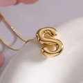 Golden balloon style letter S pendant necklace with minimalist polished metal finish - Letter S