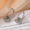 Minimalistische zilveren knoopoorbellen op beige zijden stof en een boek - Multi-ring Omwikkelde Knoop / Zilver