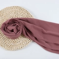 Elegant dusty pink chiffon hijab scarf neatly displayed on a rustic woven mat - 87